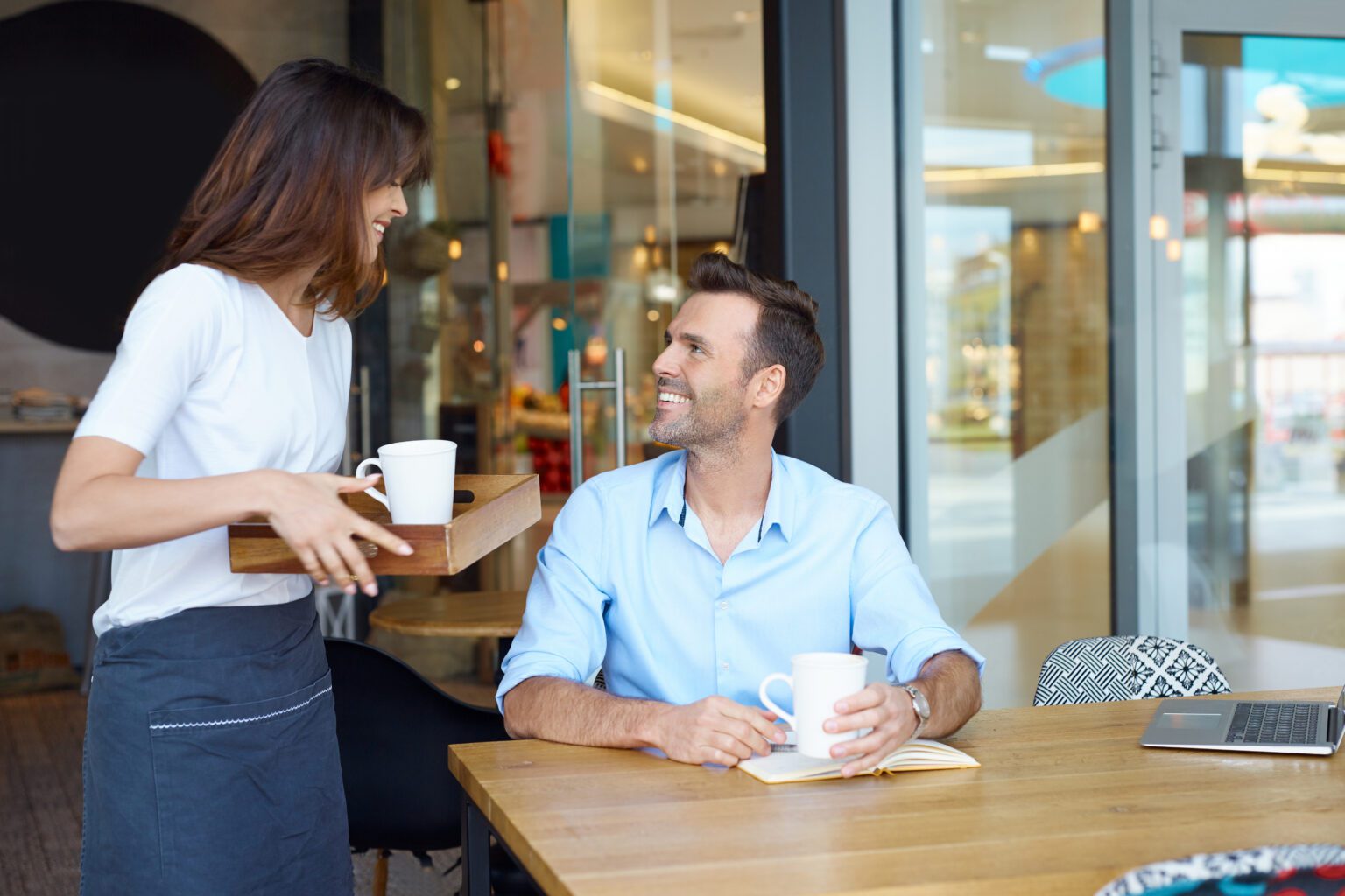 A business consultant chatting with a cafe owner at her counter